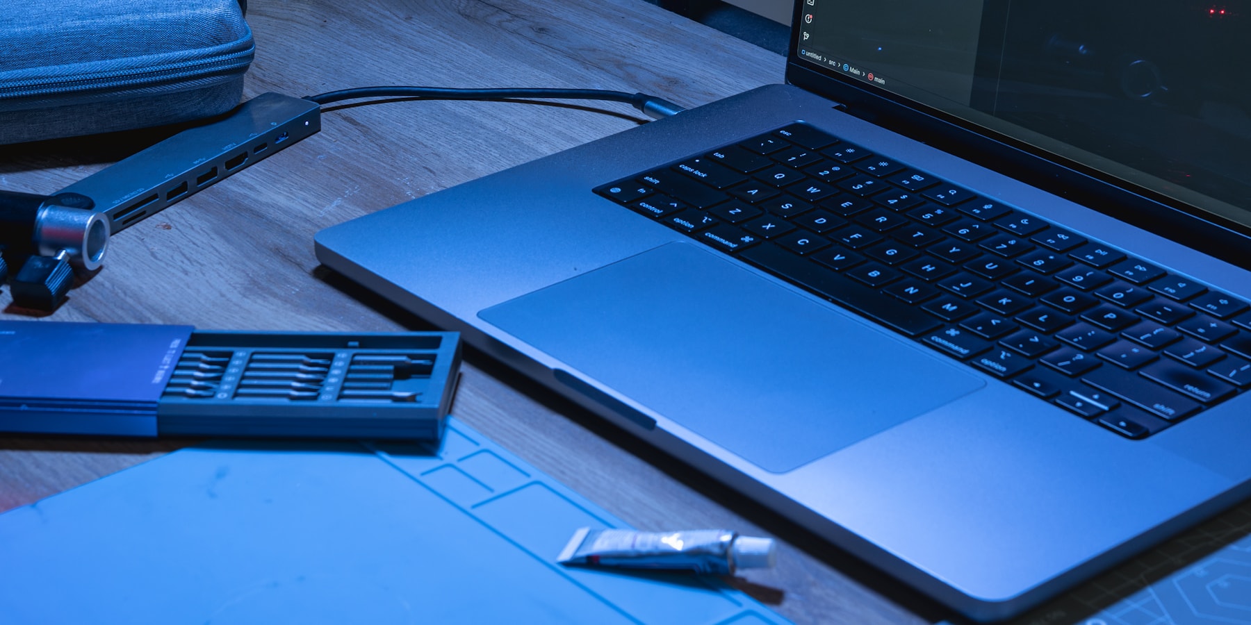 Laptop azul com código aberto sobre uma mesa de trabalho.